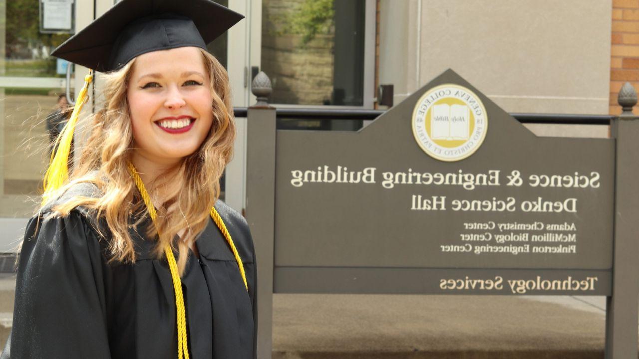 路易斯•蒙哥马利, 2019年新濠天地app毕业生, 她戴着毕业帽，穿着毕业服，站在理工科大楼的标牌旁.